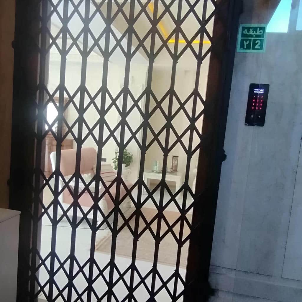 حفاظ درب آکاردئونی سفید کنار چارچوب آپارتمان حفاظ درب آکاردئونی سفید کنار چارچوب آپارتمان
