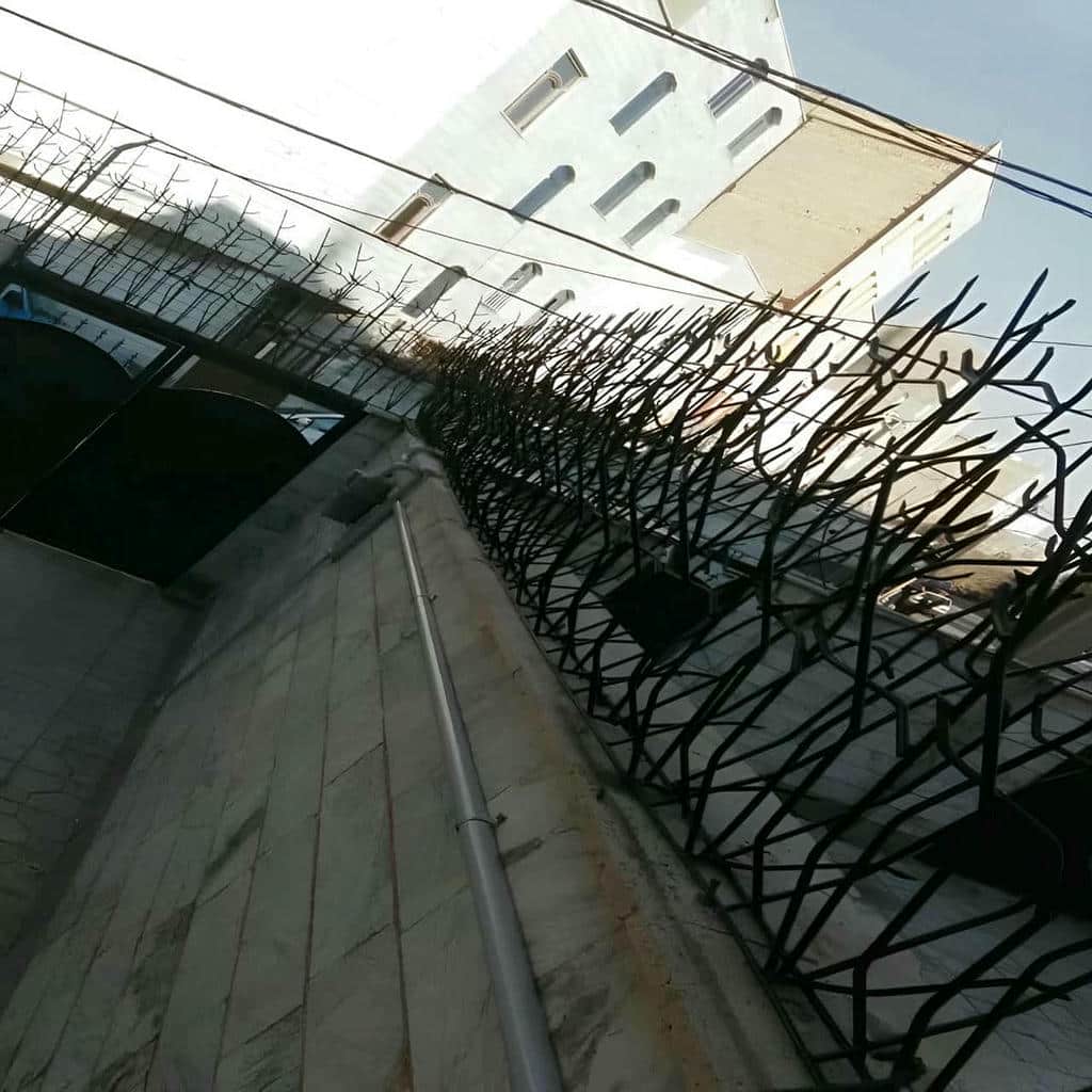 نرده سرنیزه‌ای خاکستری بالای حصار سیمانی حیاط